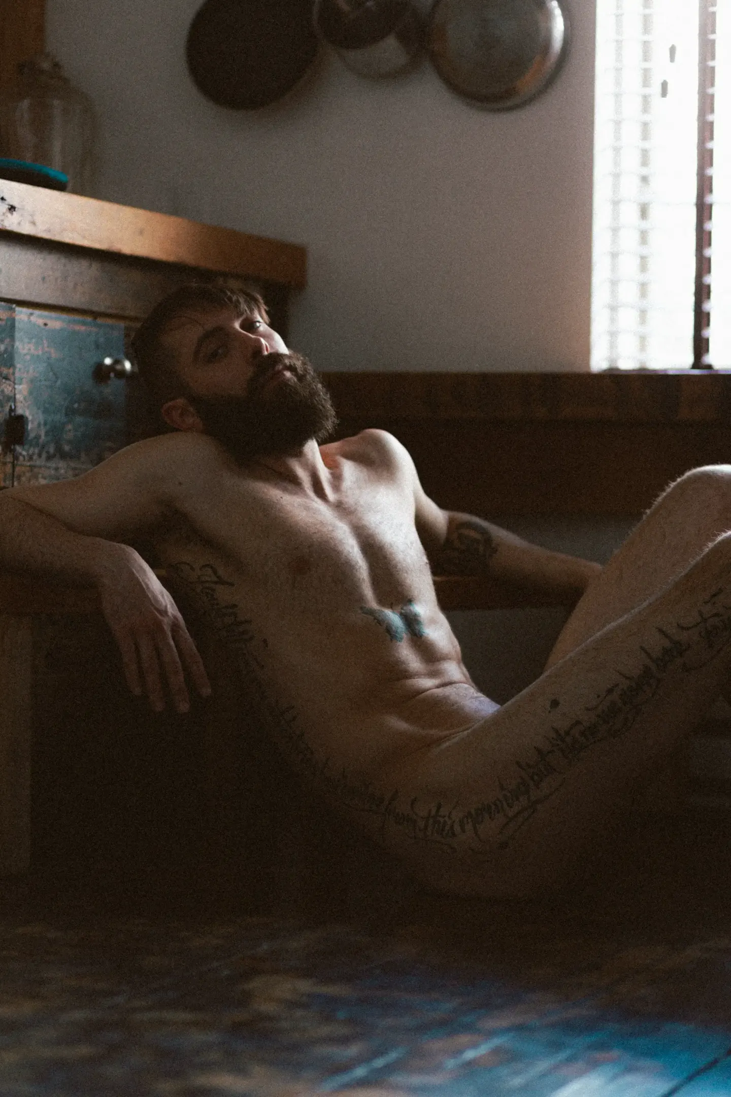 Portrait boudoir masculin chalet — nu tatoué lumière naturelle Belle Tronche
