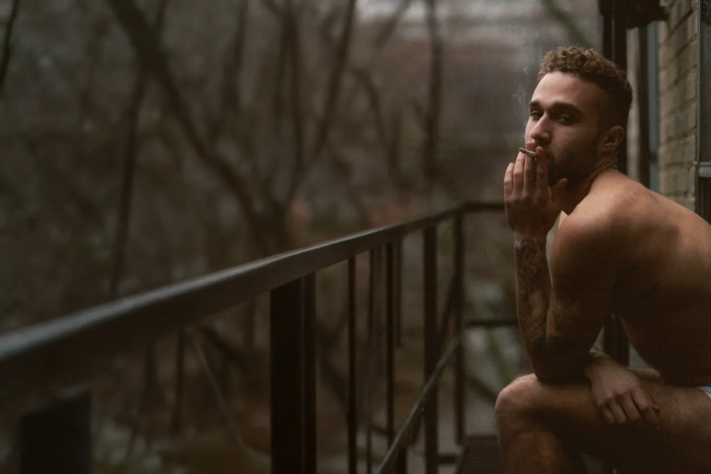 Homme en sous-vêtements sur un balcon, ville en arrière-plan — boudoir homme Montréal